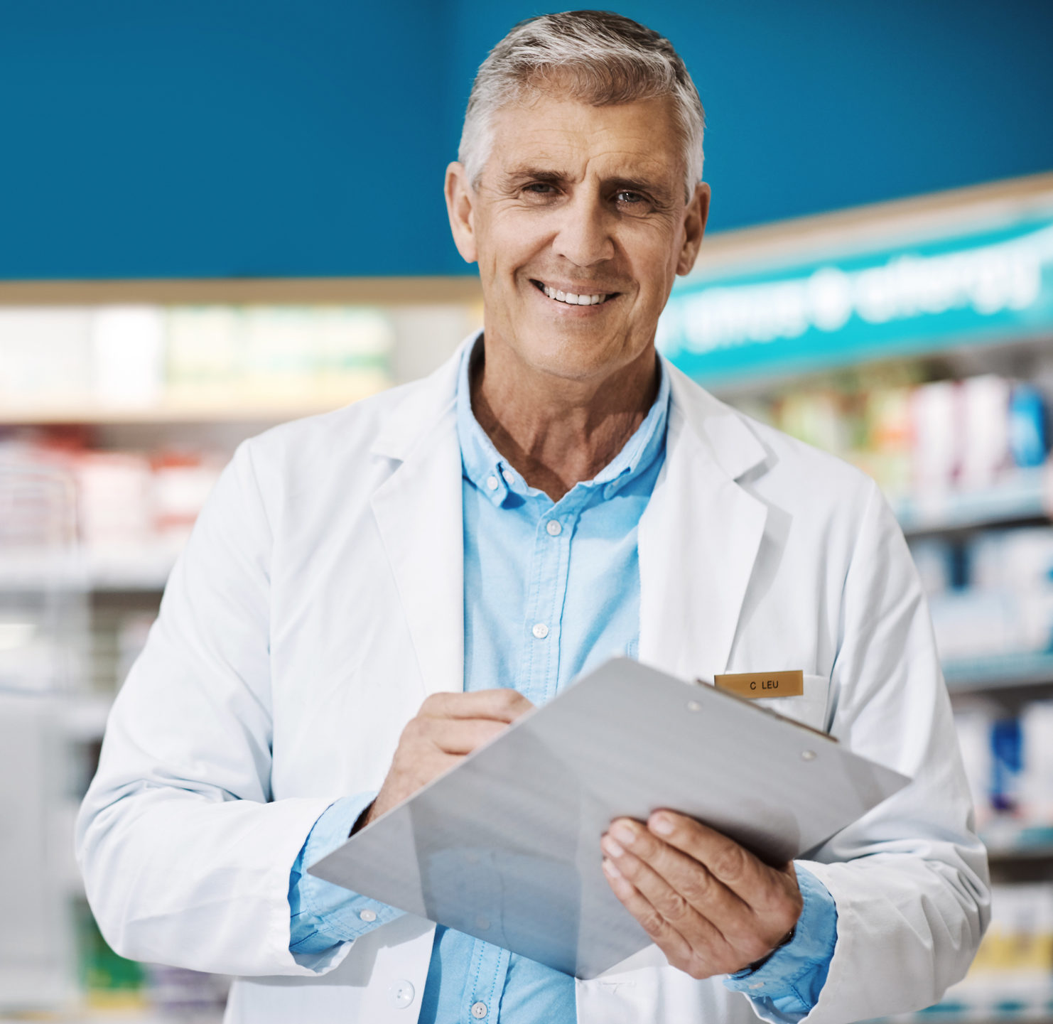 male pharmacist writing on a clipboard in a drugstore